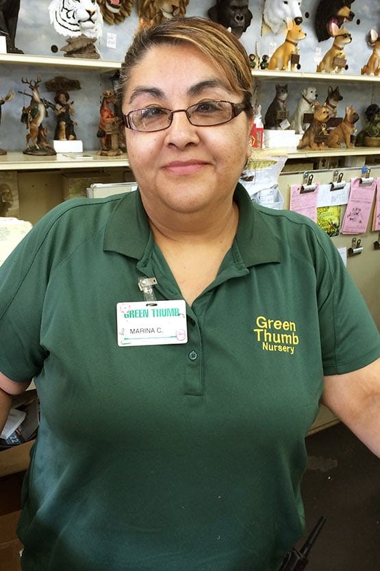 A woman in a green shirt standing in front of a store.