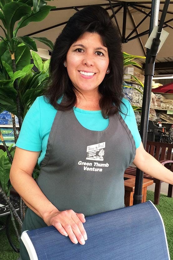 A woman in an apron standing next to a patio table.