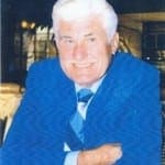 A man in a blue suit sitting at a table.