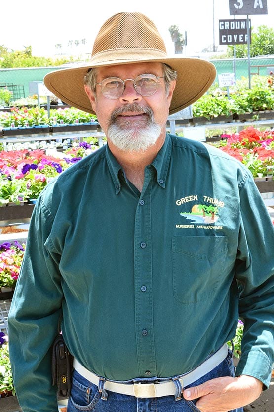 A man in a hat standing in front of a flower shop.
