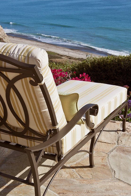 A chaise lounge on a patio overlooking the ocean.
