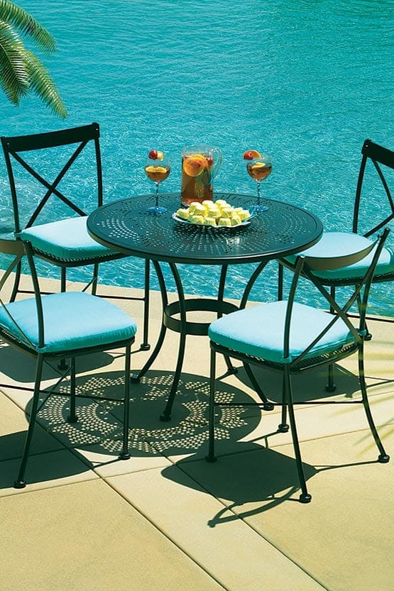 A black wrought iron dining set with blue cushions.