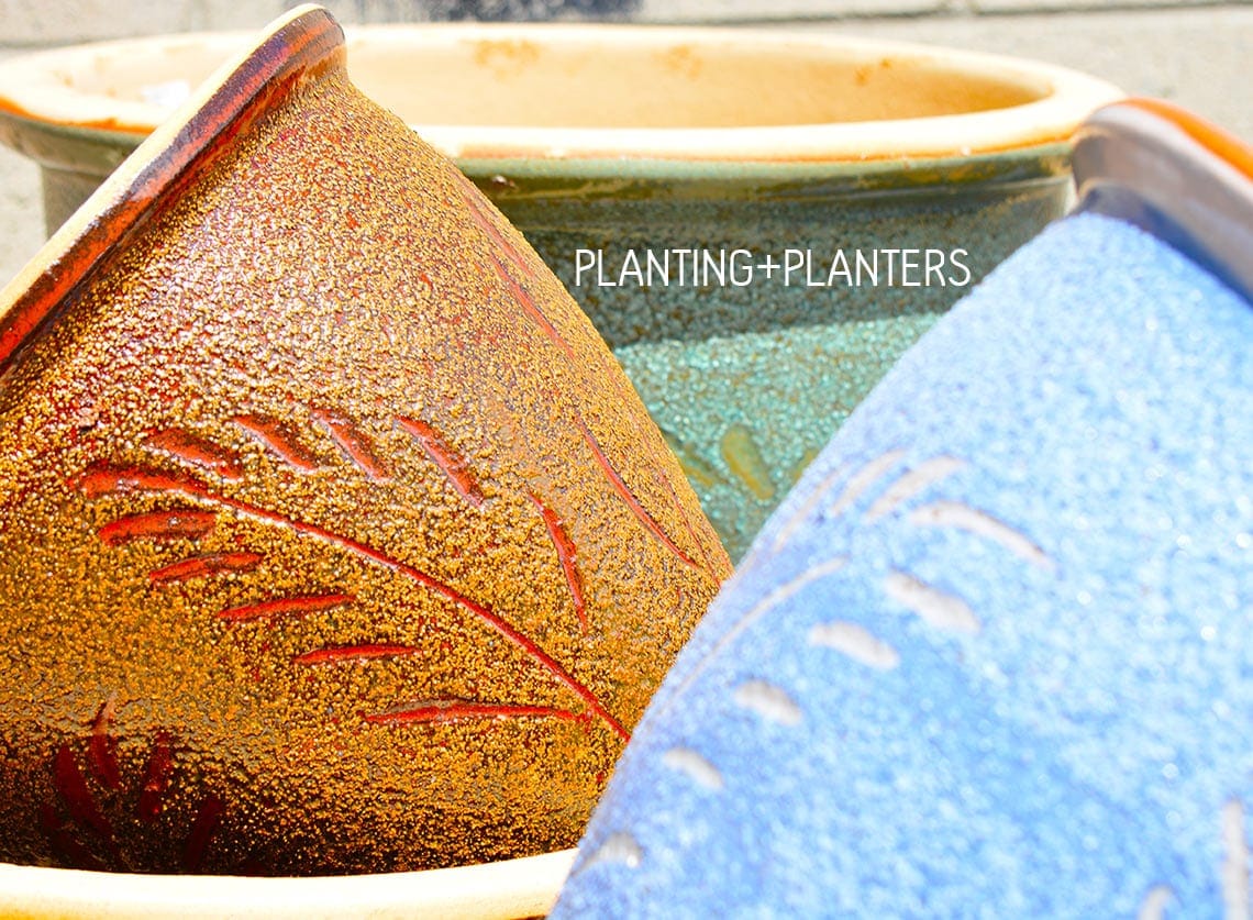 A group of colorful ceramic pots sitting on a brick wall.