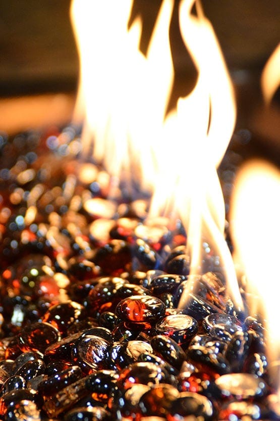 A fire pit with red and black pebbles and flames.