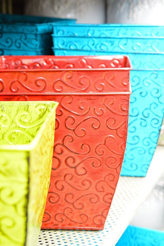 A row of colorful flower pots on a shelf.