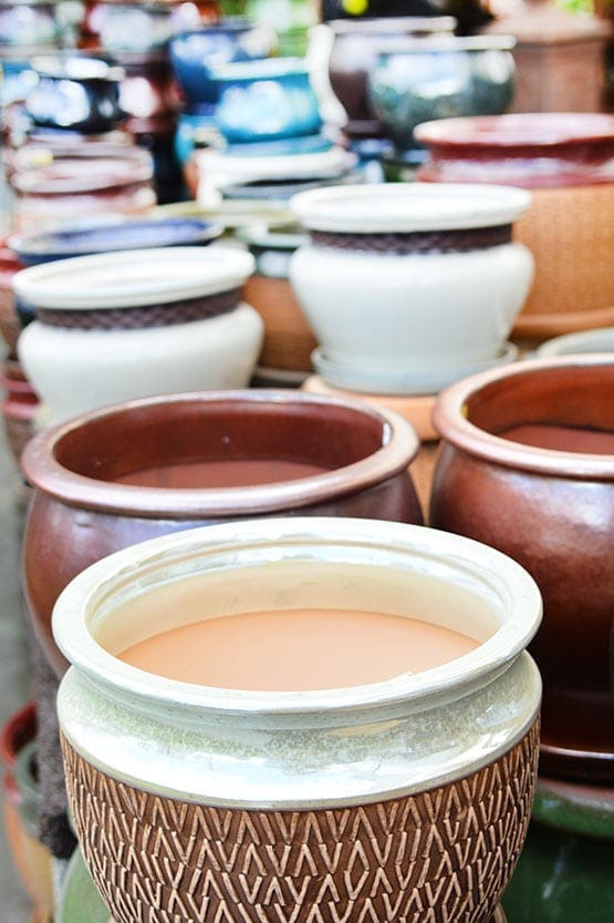 Many pots are sitting on a table in front of a store.