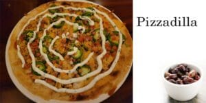 A pizza on a plate next to a cup of olives at the best garden center near me.