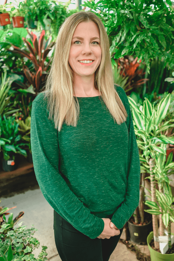 A woman standing in front of potted plants at a garden center.
