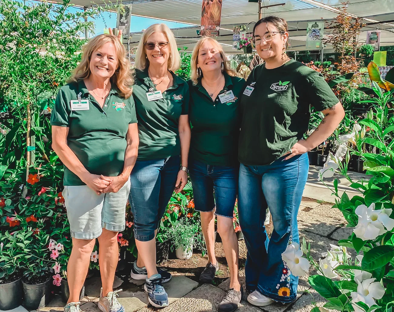 Four women in green shirts standing in front of plants at a garden center near me.