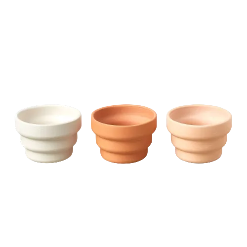 Three vibrant-colored pots on a sleek black background.
