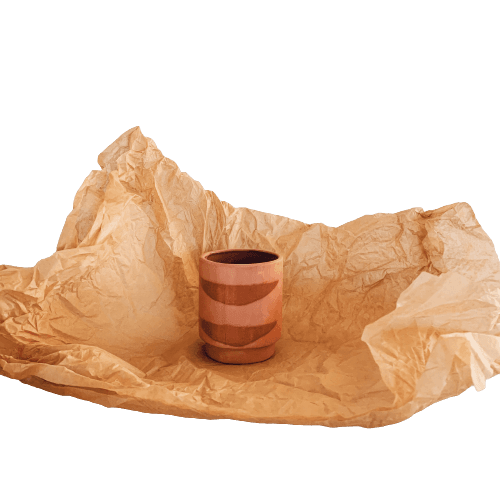 A cup sitting on top of a piece of brown paper in a garden center.