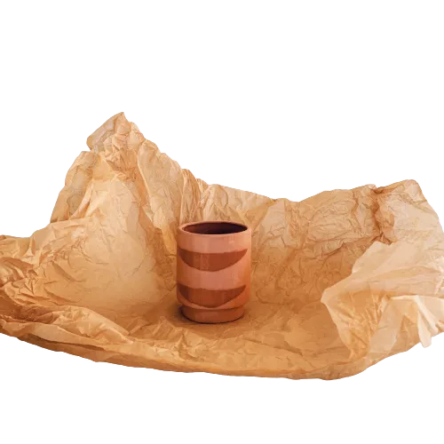 A cup sitting on top of a piece of brown paper in a garden center.